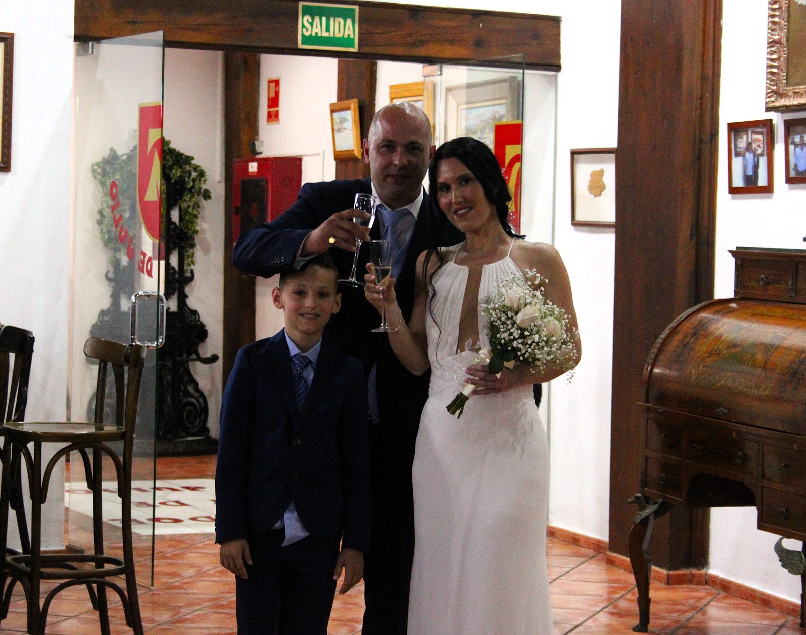 Gli sposi e il figlio brindano all'ingresso